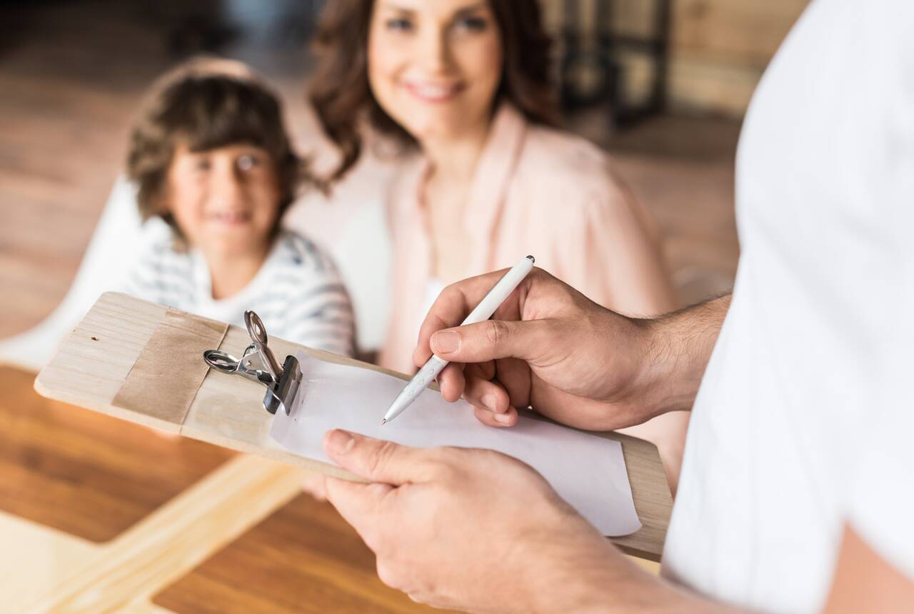 Przykładowe zdjęcie osoby wypełniającej formularz. W tle mama z dzieckiem na kolanach.