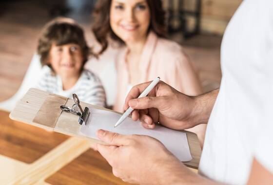 Przykładowe zdjęcie osoby wypełniającej formularz. W tle mama z dzieckiem na kolanach.