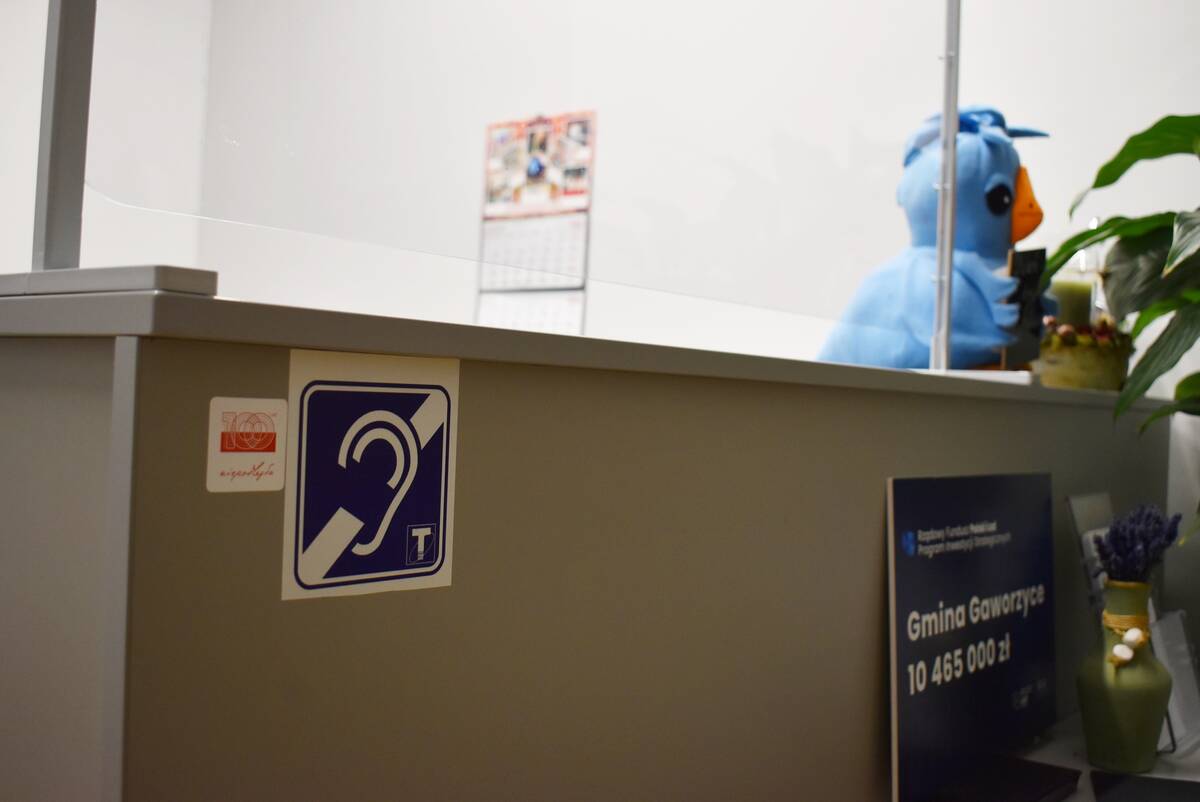Zdjęcie z Sekretariatu Urzędu Gminy w Gaworzycach z naklejką informacyjną o działającej tu pętli indukcyjnej.